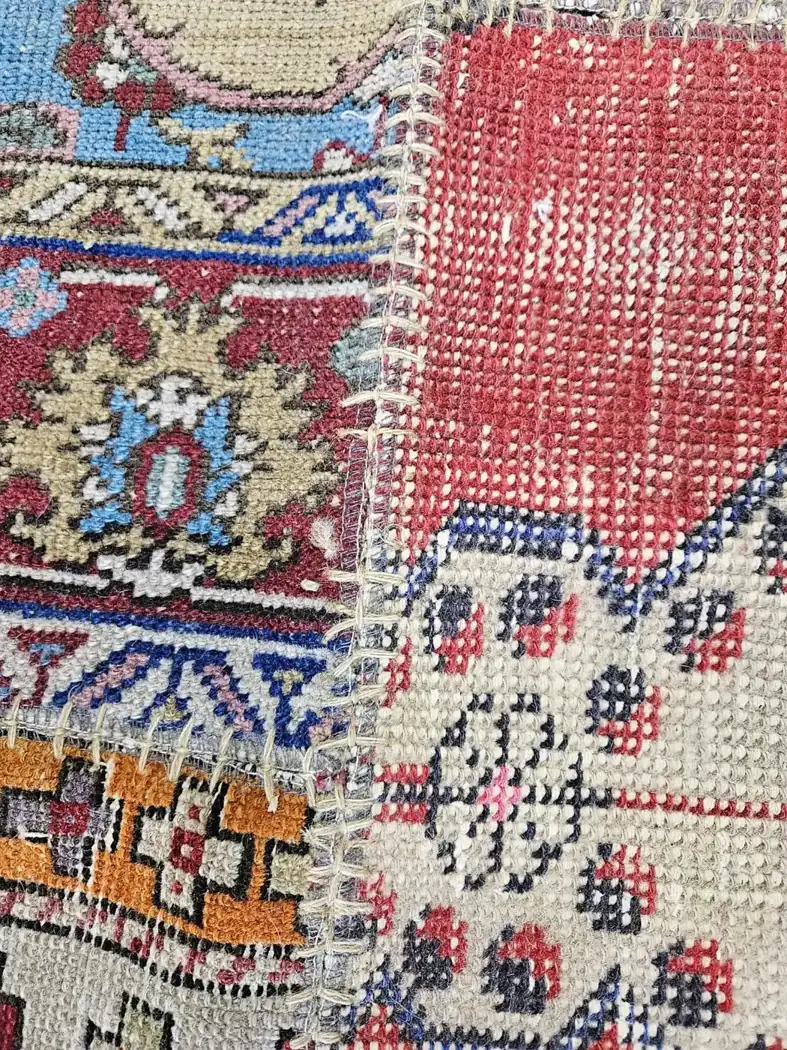 Antique rug made up of separate fragments joined by earlier hand repairs