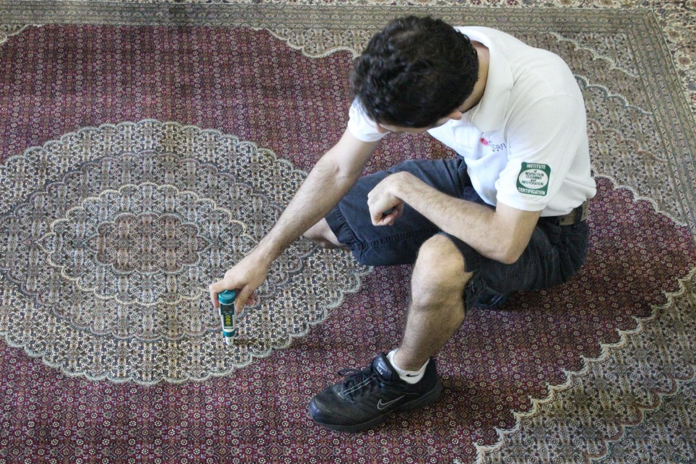 Technician performing a dye-stability test on a fine Persian rug before washing