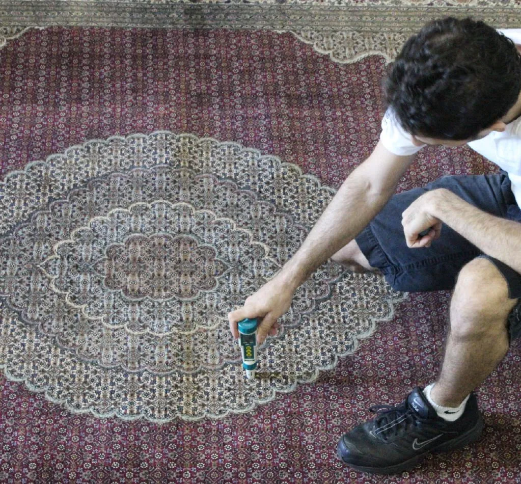 Technician testing dye stability on a Persian rug with a meter