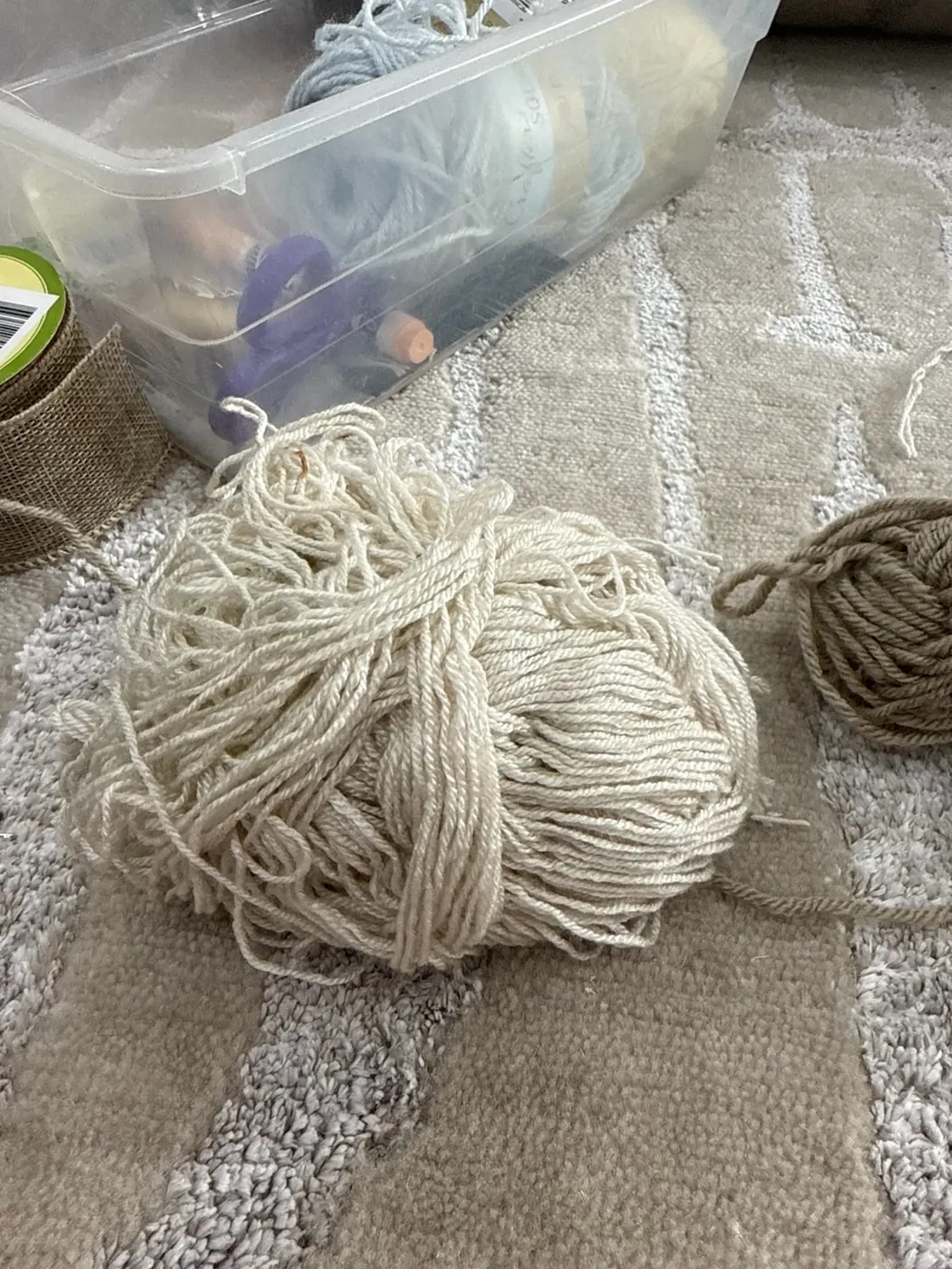 Skeins of undyed wool yarn resting on a rug at the repair bench