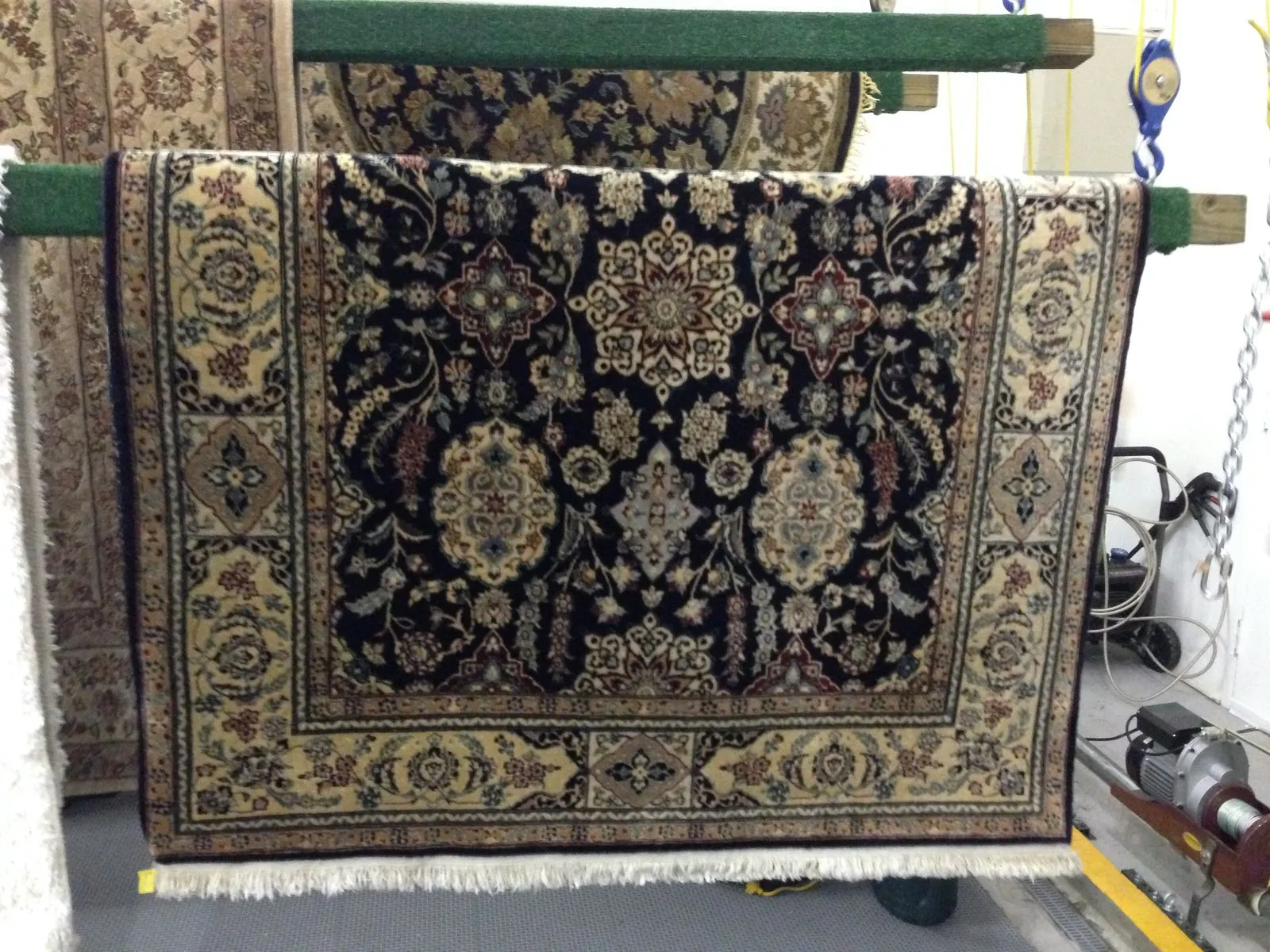 Hand-knotted rugs hanging on drying racks at the plant