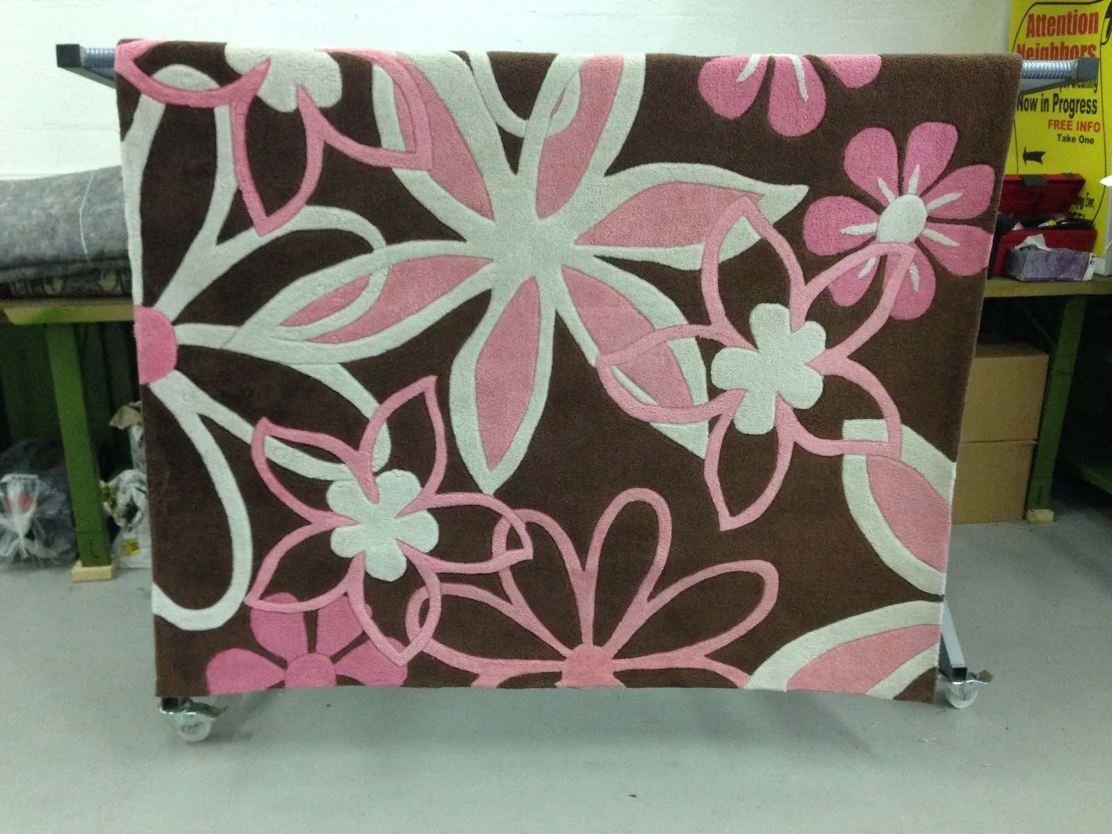 Pink and brown hand-tufted rug on a rolling rack inside the plant